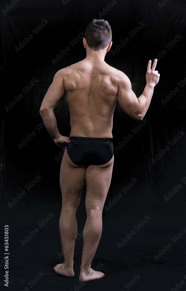 Full body shot of muscular young man seen from the back