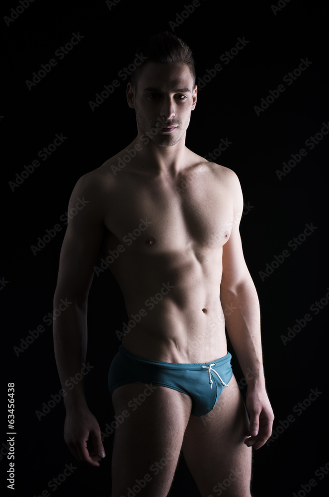 Chiaroscuro photo of shirtless young man standing