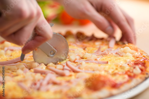 Pizza carbonara portions cutting by round knife
