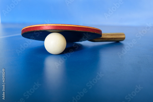 Pin pong ball with red paddle on blue board