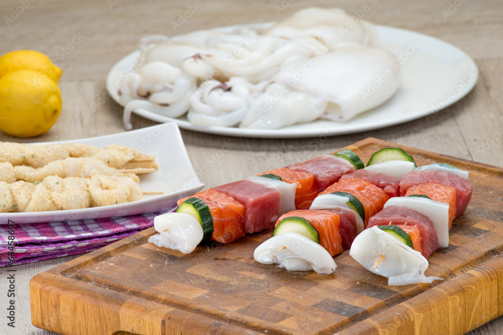 Spiedini di pesce misto crudi posti su un tagliere di legno Stock Photo