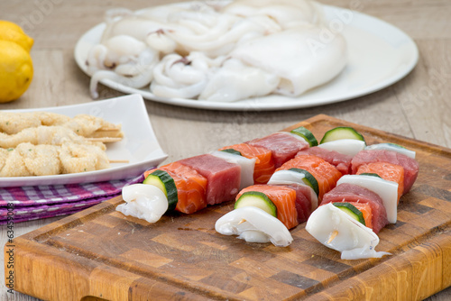 Spiedini di pesce misto crudi posti su un tagliere di legno photo