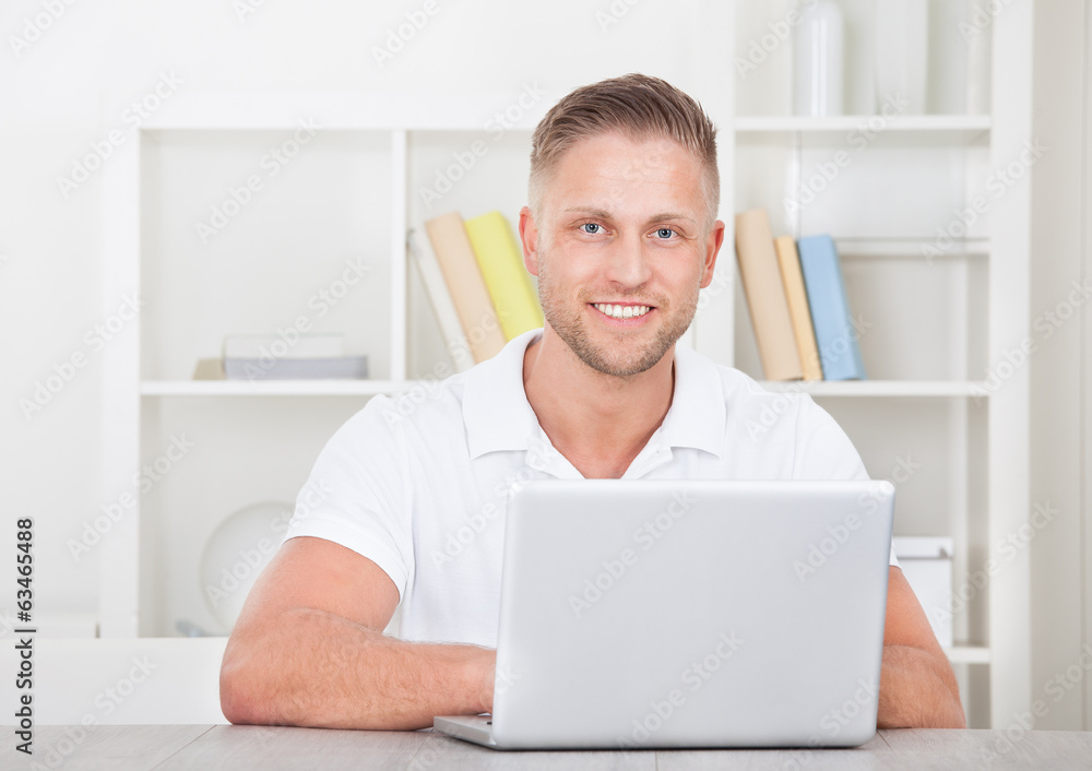 Smiling young man in a short sleeved shirt sitting working Smiling young man in a short sleeved shirt sitting working