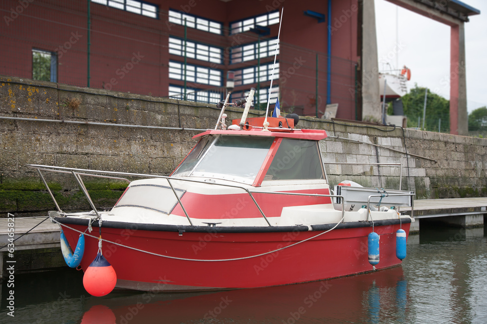 Floating small red motorboat at the dock