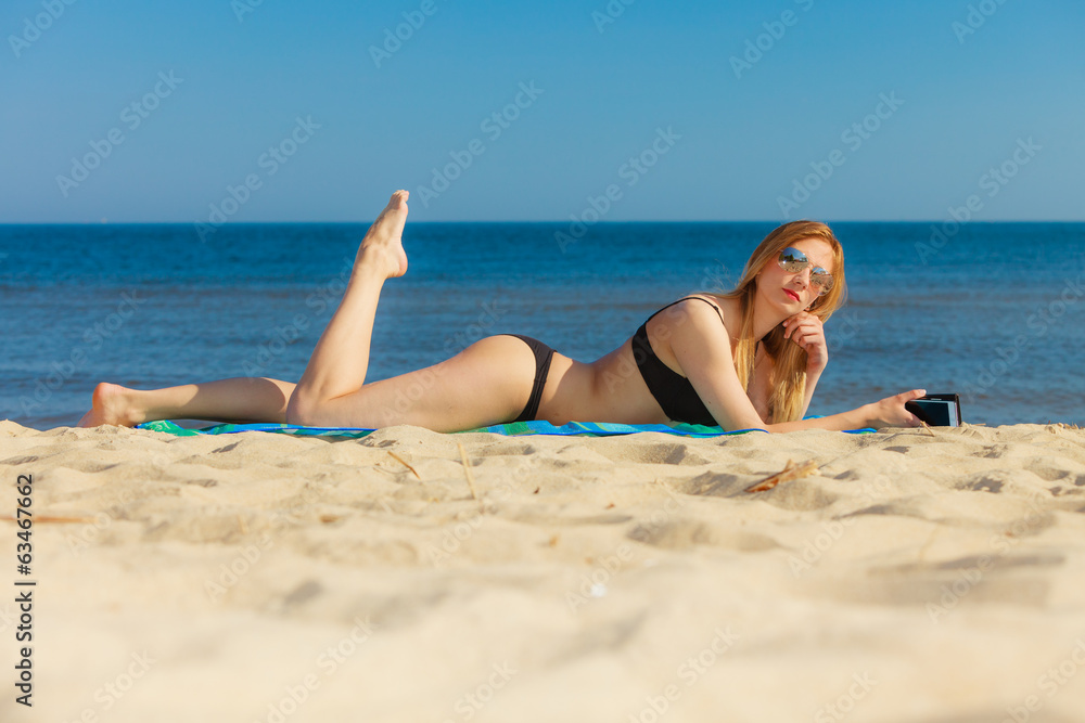 Summer vacation Girl with phone tanning on beach Summer vacation Girl with phone tanning on beach