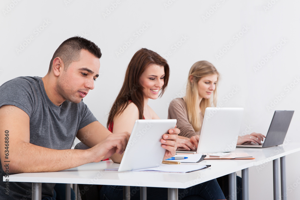 Confident Male Student Holding Digital Tablet At Desk Confident Male Student Holding Digital Tablet At Desk