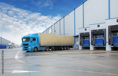 Fototapeta Unloading cargo truck at warehouse building