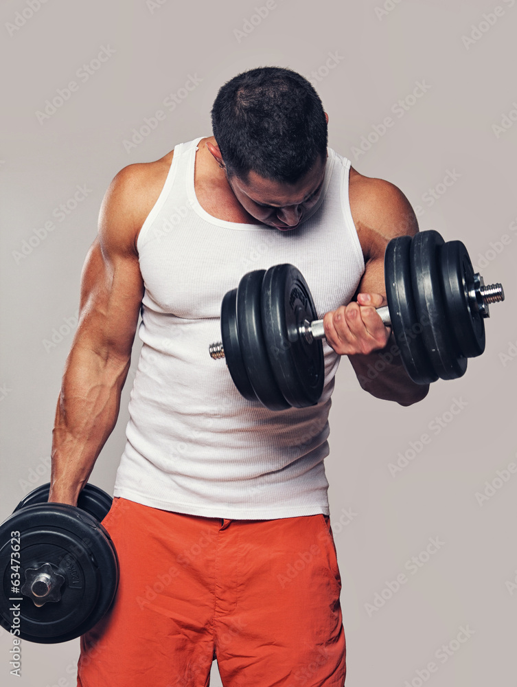 Fit muscular man exercising with dumbbells Fit muscular man exercising with dumbbells