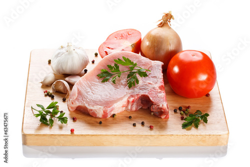 Raw pork on cutting board and vegetables