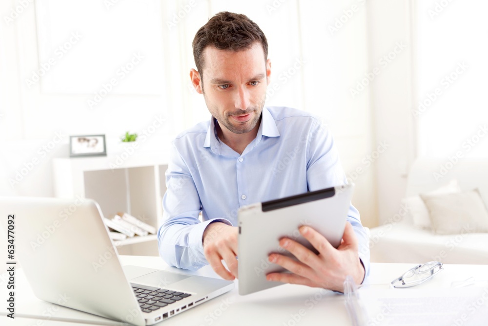Young business man working at home on his tablet Young business man working at home on his tablet