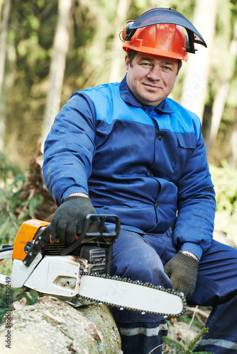 Lumberjack worker with chainsaw in the forest