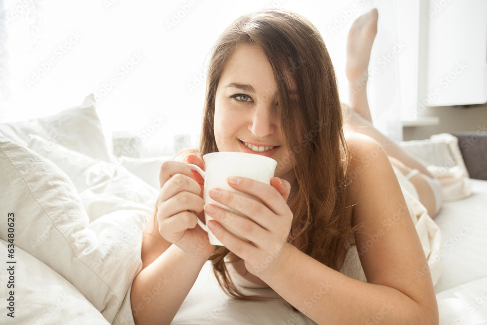 smiling woman drinking coffee in bed at morning smiling woman drinking coffee in bed at morning