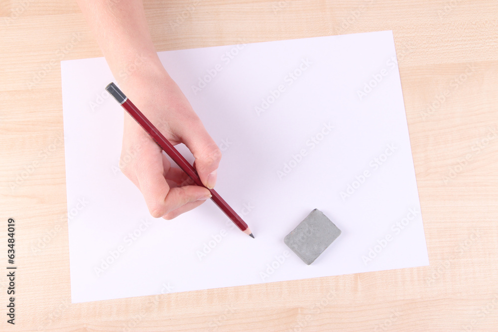 Hand holding pencil and erase with paper on wooden background Hand holding pencil and erase with paper on wooden background