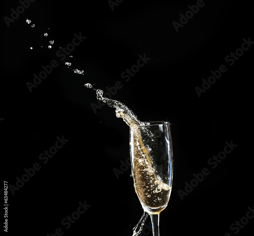 Glass of champagne with splash, on black background