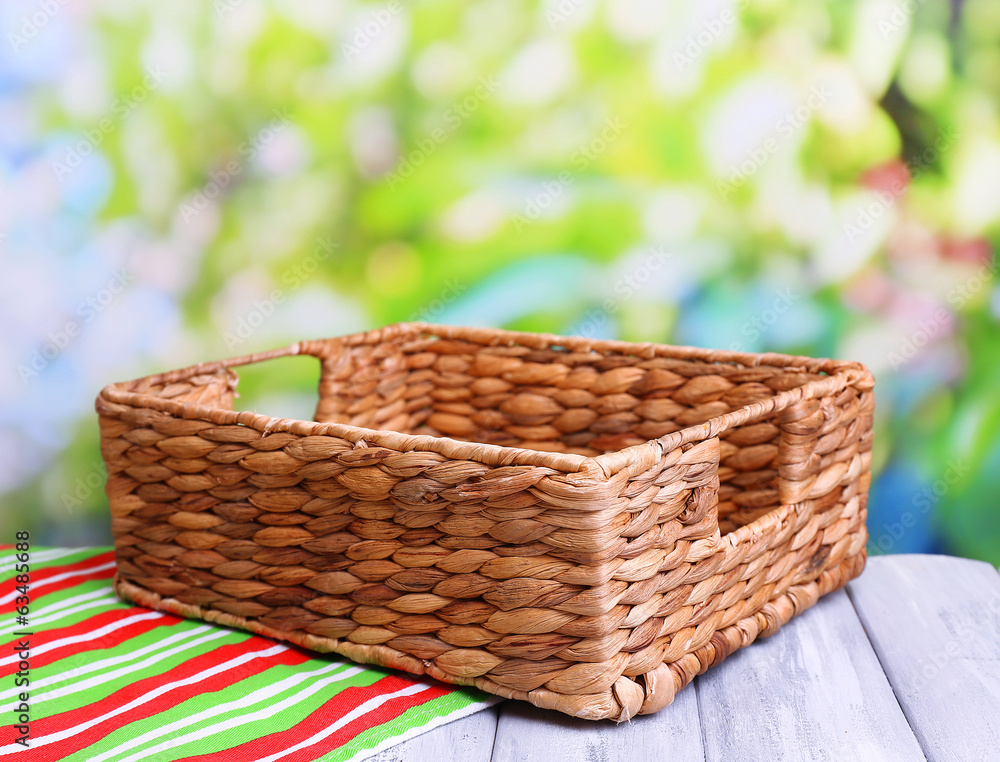 Empty wicker basket on wooden table, on bright background Empty wicker basket on wooden table, on bright background