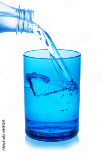 Bottle pouring water into glass on white background.