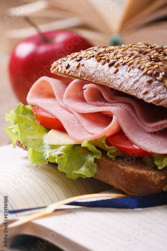 Lunch: sandwich with ham and red apple on notebook photo