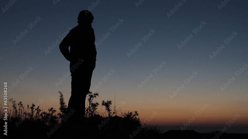 Silhouetted man standing in sunset on mountain Silhouetted man standing in sunset on mountain