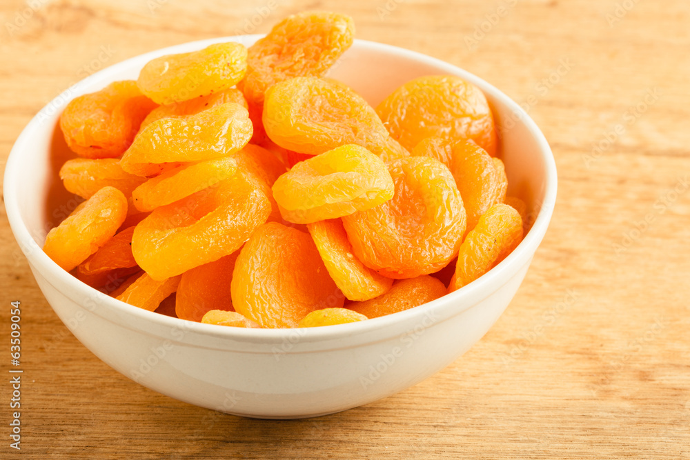 Bowl of dried apricots on wooden table background. Bowl of dried apricots on wooden table background.