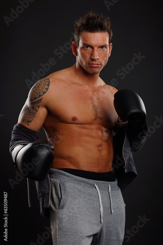Handsome muscular man poses with boxer gloves