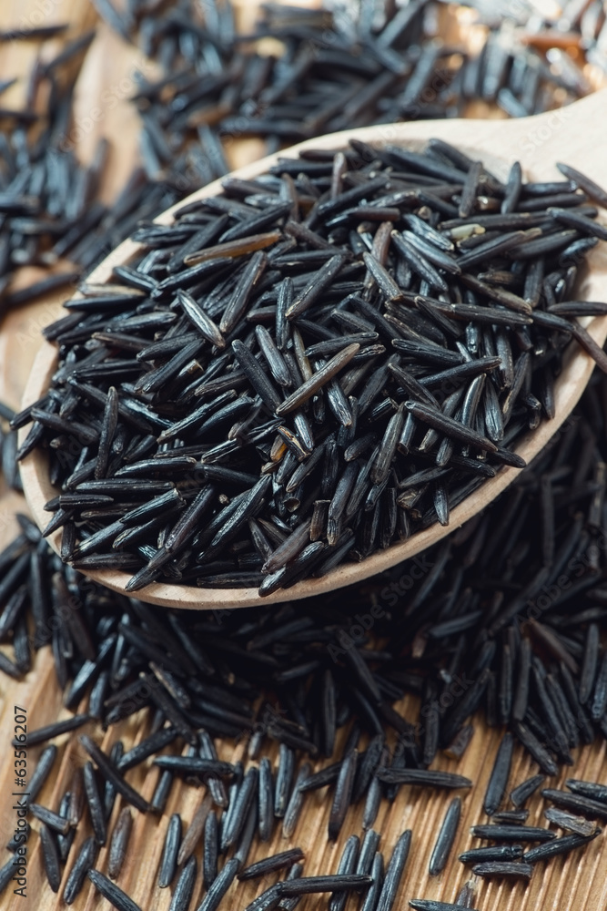 Vertical shot of raw wild rice in a wooden spoon, close-up Vertical shot of raw wild rice in a wooden spoon, close-up