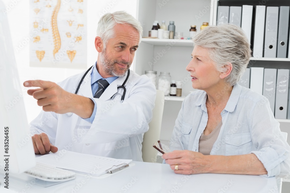 Doctor with female patient reading reports on computer Doctor with female patient reading reports on computer