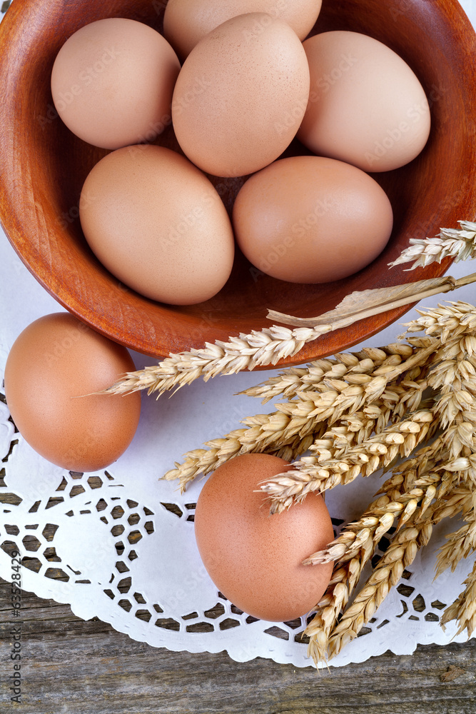 Eggs in wooden bowl with spikes of wheat Eggs in wooden bowl with spikes of wheat