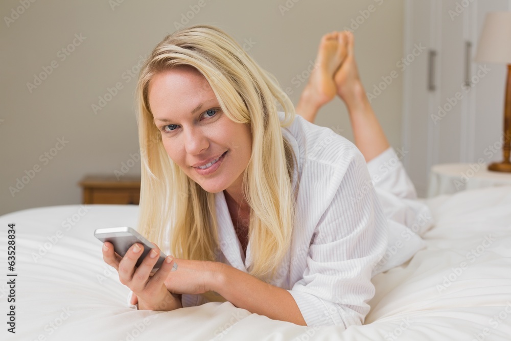 Woman holding mobile phone while lying in bed Woman holding mobile phone while lying in bed