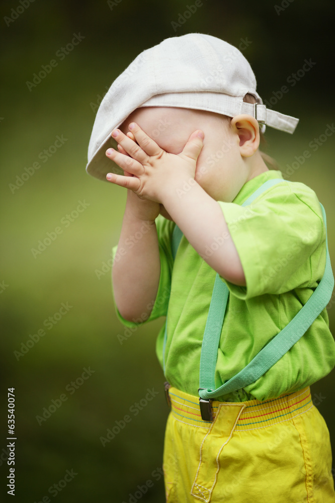 Fotografie little boy plays hide and seek