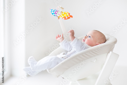 Cute newborn baby boy watching a colorful mobile toy