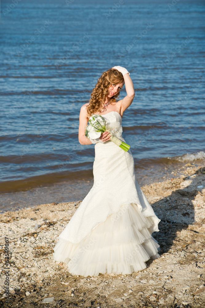 Beautiful bride in a white dress on coast of river Beautiful bride in a white dress on coast of river