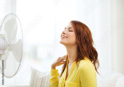 smiling redhead teenage girl with big fan at home photo