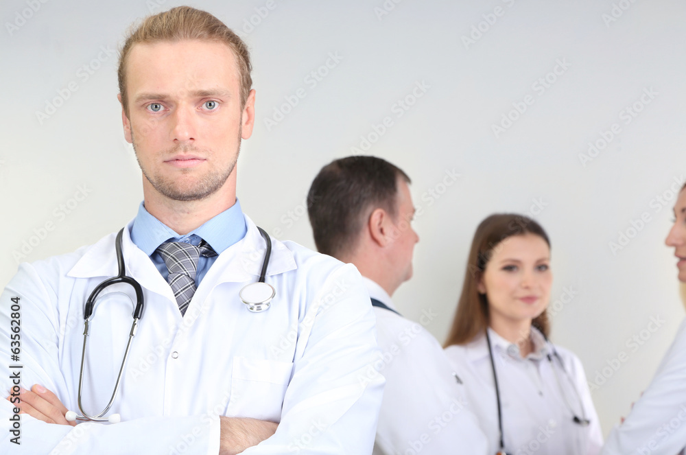 Doctor standing in front of coworkers on grey background Doctor standing in front of coworkers on grey background