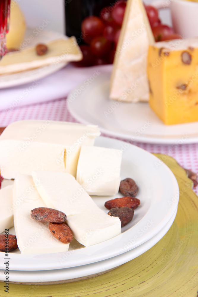 Assorted cheese plate on pink tablecloth background, close-up Assorted cheese plate on pink tablecloth background, close-up