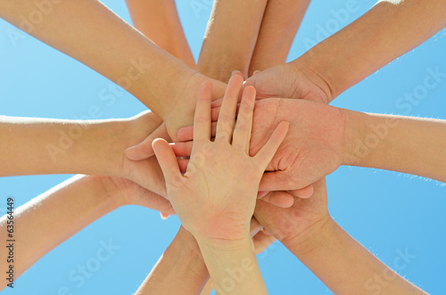 Many hands together over blue sky.