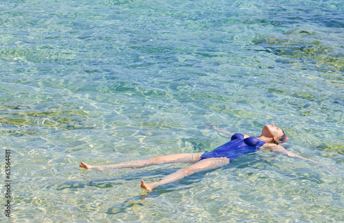 Pretty woman swimming in transparent turquoise sea.
