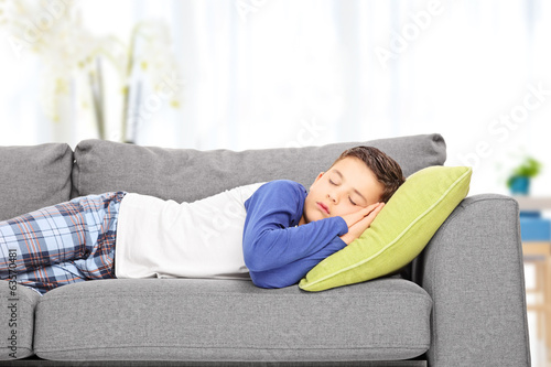 Cute little boy sleeping on sofa indoors