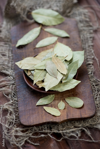 Dried bay leaves on a wooden chopping board, vertical shot