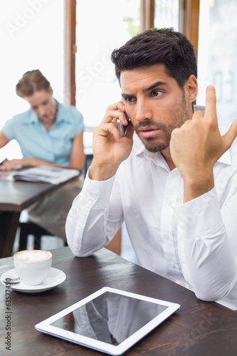 Serious man using mobile phone in coffee shop