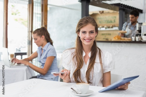 Smiling woman using digital tablet in coffee shop