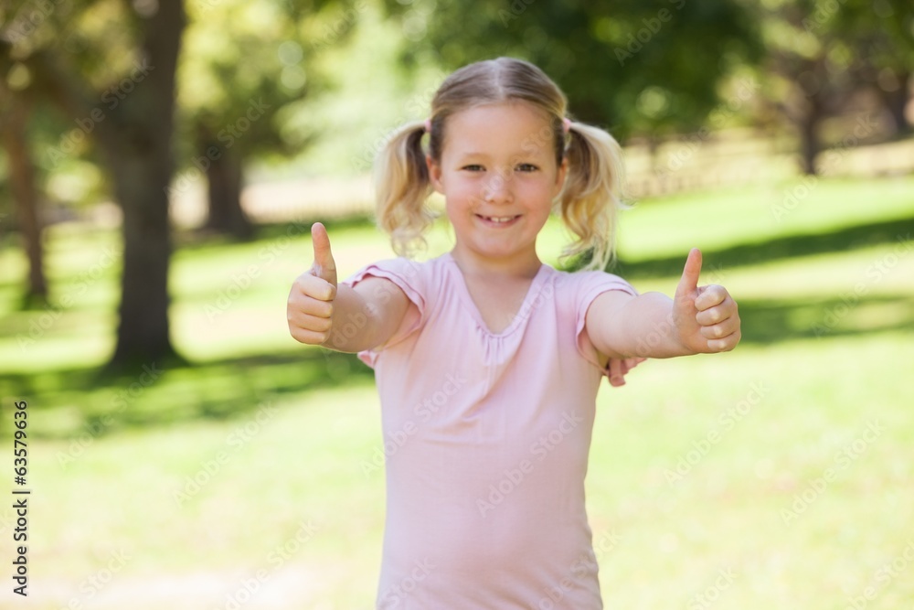 Smiling young girl gesturing thumbs up at park Smiling young girl gesturing thumbs up at park