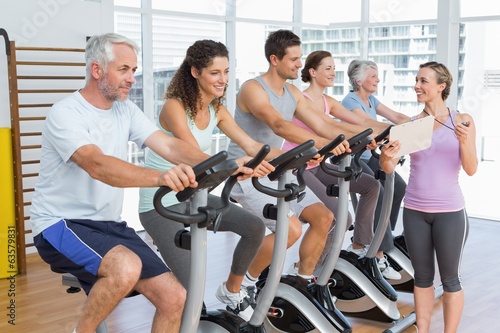 Trainer besides people working out at spinning class