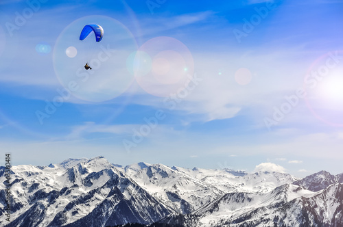 Winter mountains landscape and man paragliding