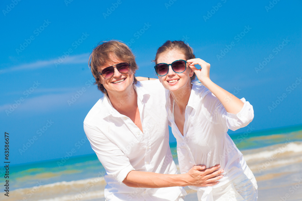 Closeup of happy young couple in white clothes and sunglasses Closeup of happy young couple in white clothes and sunglasses