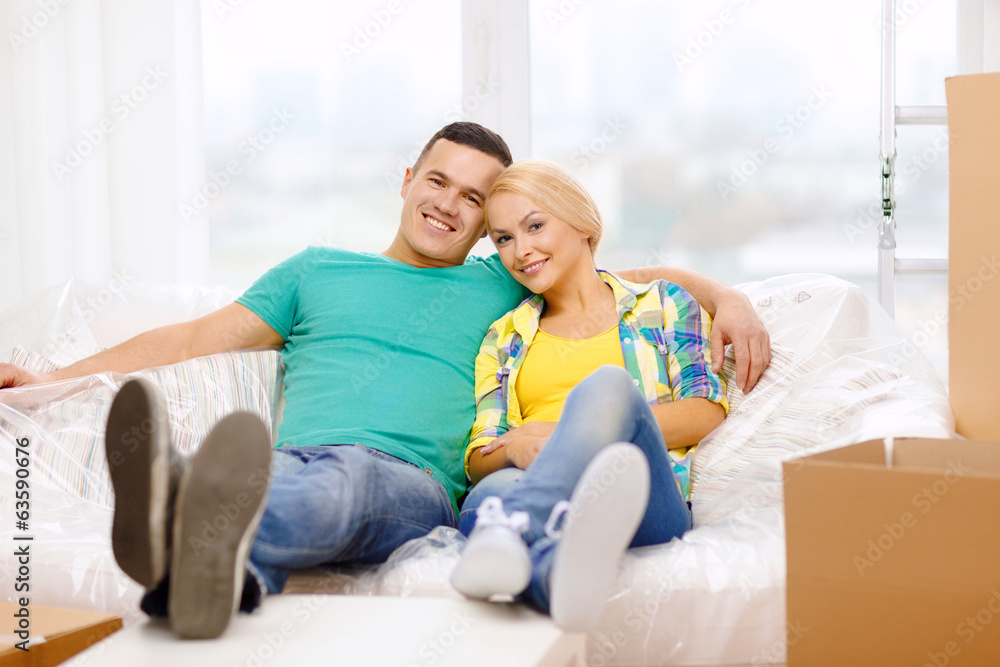 smiling couple relaxing on sofa in new home