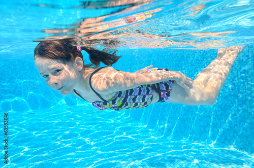 Happy active underwater child swims in pool, girl swimming