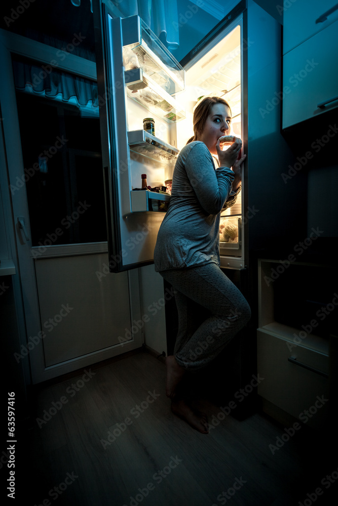 hungry woman eating at night near refrigerator hungry woman eating at night near refrigerator