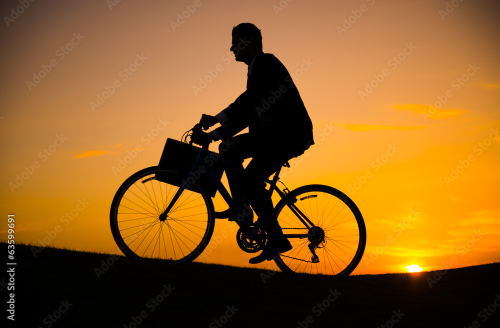 Fototapeta premium Businessman riding bicycle on the hill