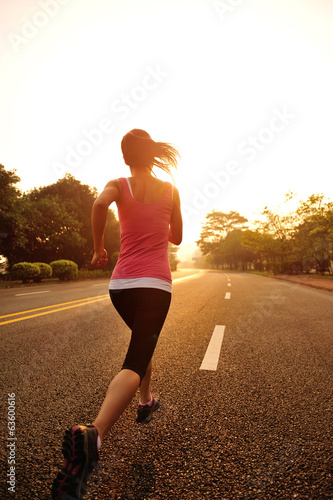 young fitness woman running at sunrise driveway