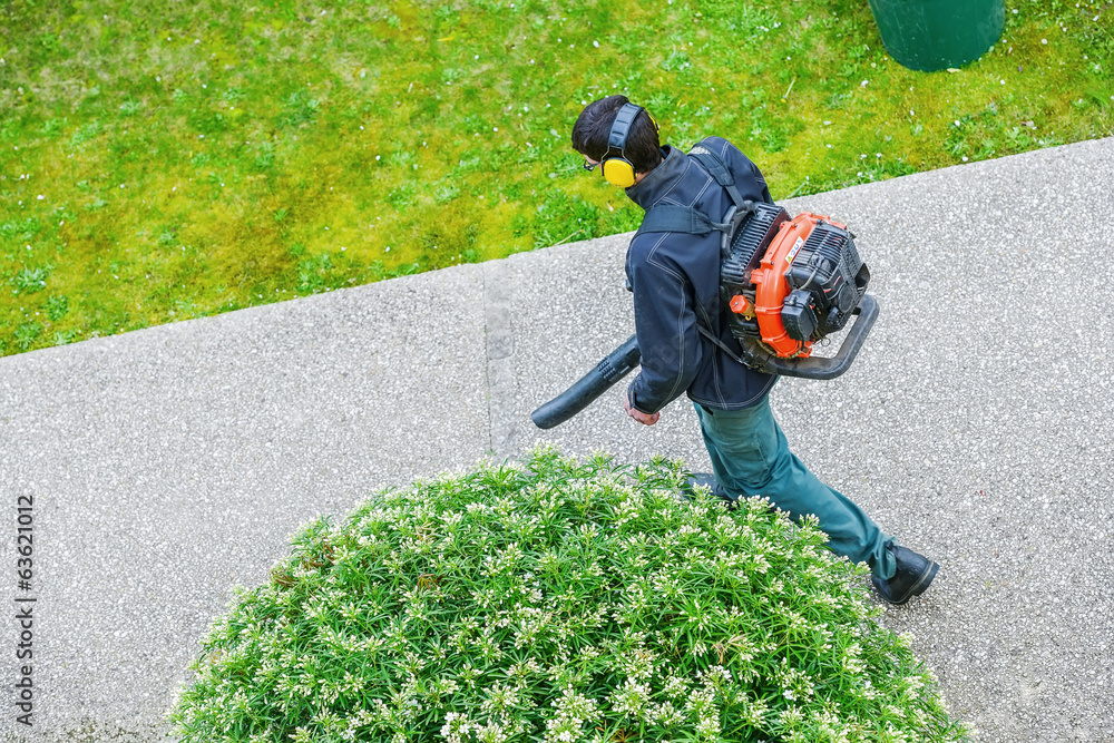 Naklejka premium gardener using a gas blower in a park